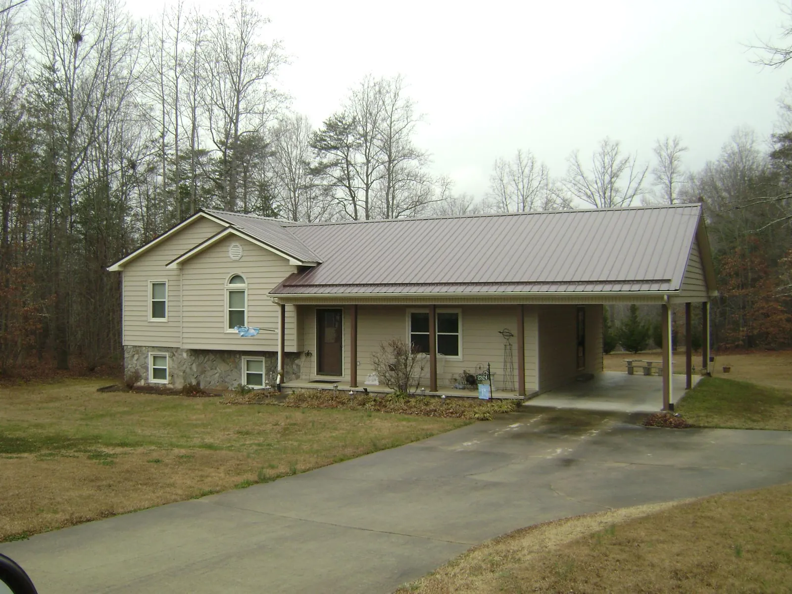 Brown metal roof on a tan split level home with an attached carport in Kempton