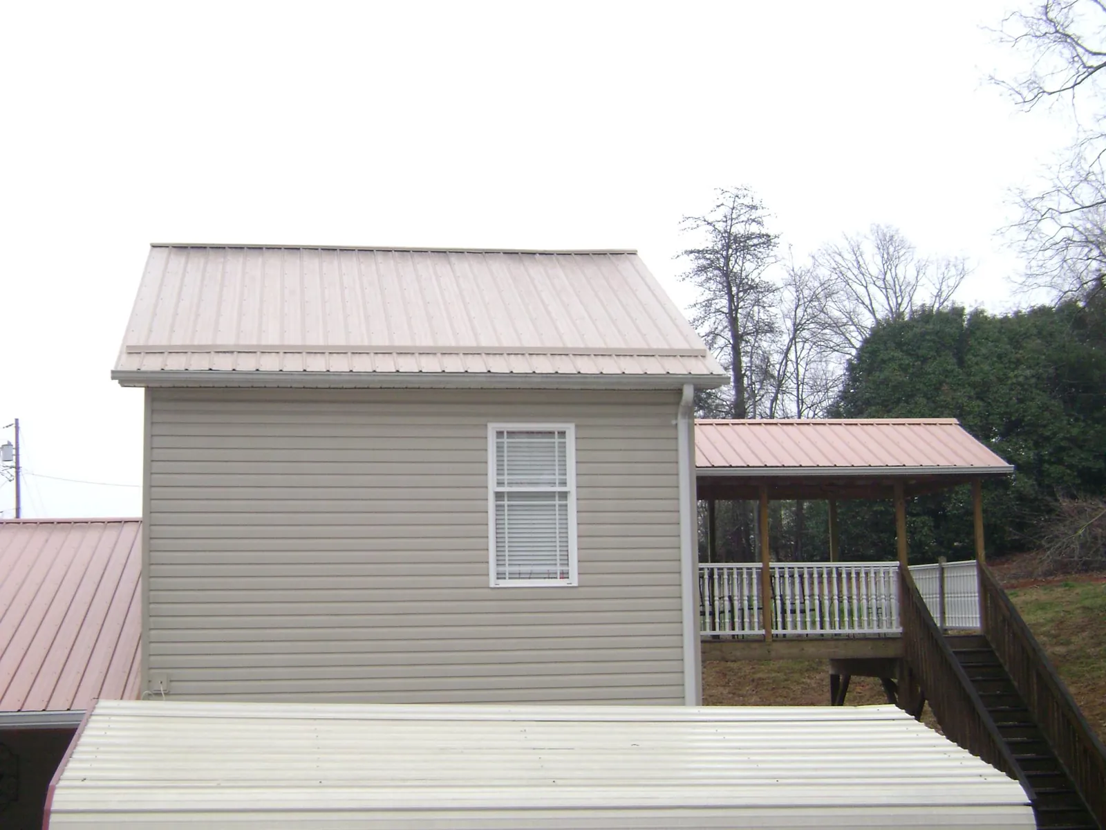 Tan metal roofs on a two story addition and attached porch, from a Roof Replacement job in Kempton