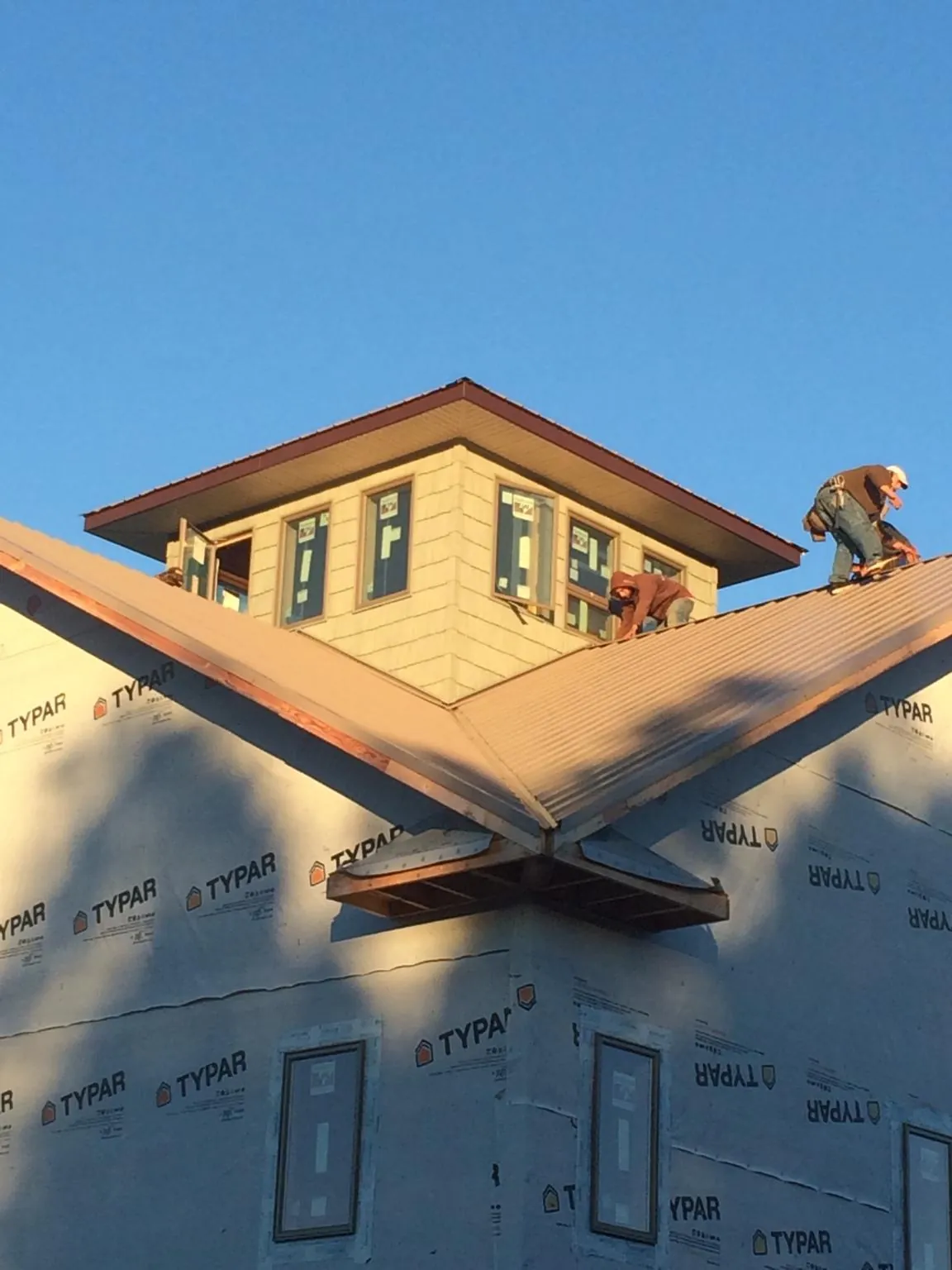 Roofers working around a rooftop cupola on a new metal roof at sunset — Roof Waterproofing in Kempton by Roofing Brothers